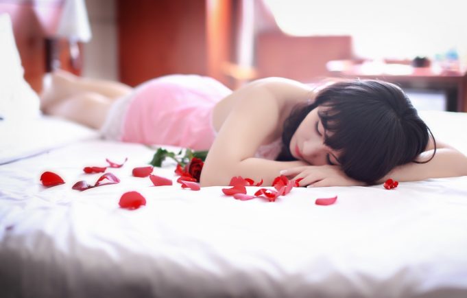 Woman lying on a bed with rose petals - Sexual attraction, intimacy and keeping your romance alive when your partner transitions. – Trans Partners by U.A. Nigro